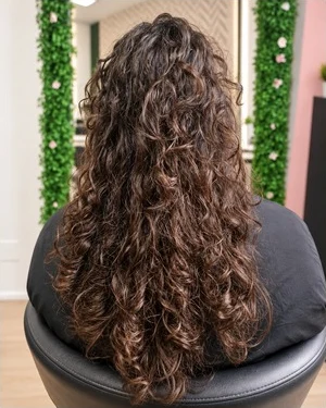 Ponto de partida do caso Alisamento C, com cabelo comprido e encaracolado visto de costas.