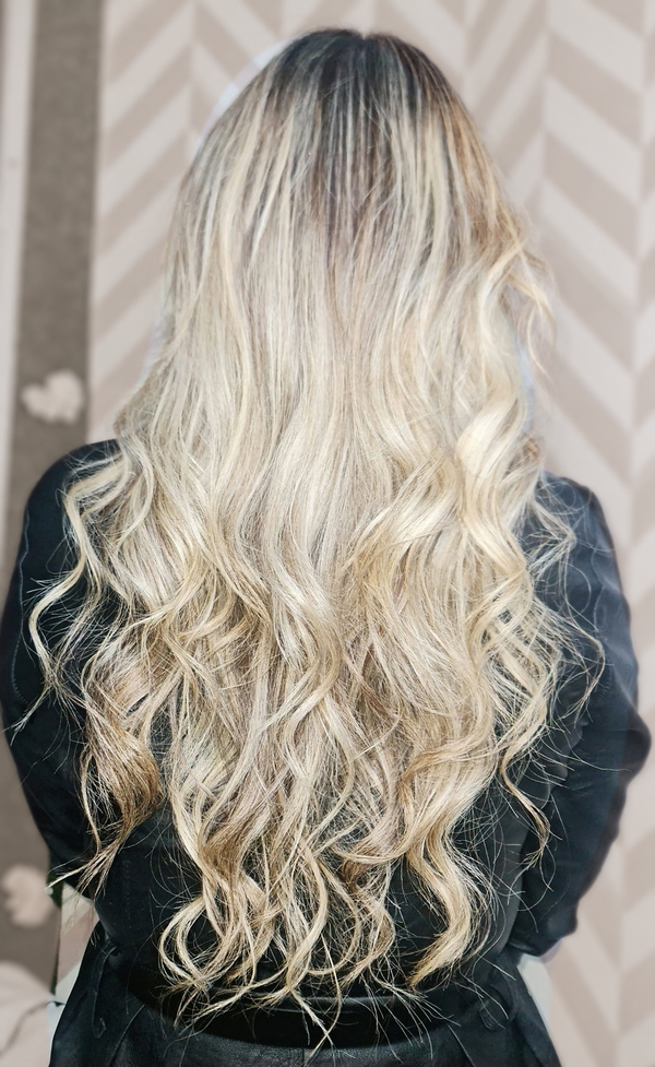 Resultado de correção de cor em cabelo loiro comprido e ondulado, visto de costas.